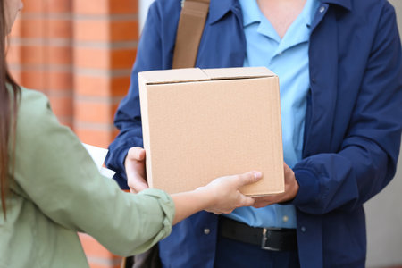 Woman parcel receiving from postman outdoorsの写真素材