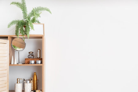 Stylish shelf unit with bath accessories near light wallの写真素材