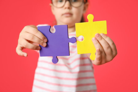 Little girl with autistic disorder and puzzle pieces on color backgroundの写真素材