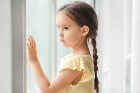 Little girl with autistic disorder near window at homeの写真素材