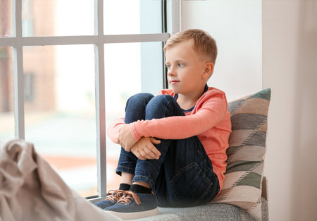 Little boy with autistic disorder sitting near window at homeの写真素材