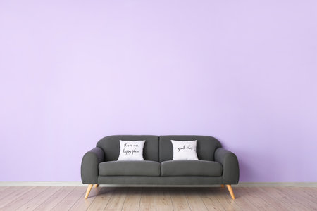 Cozy sofa with pillows near color wall in roomの写真素材