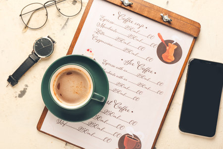 Cup of hot coffee and mobile phone on table in cafeの写真素材
