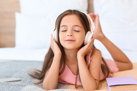 Cute little girl listening to music in bedroomの写真素材