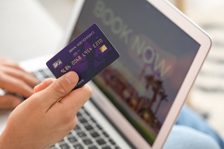 Man with laptop booking room in hotel online at homeの写真素材