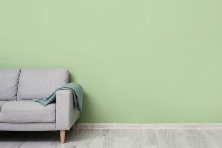 Sofa with plaid near color wall in room