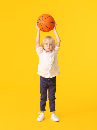 Cute sporty boy with basketball on color backgroundの写真素材