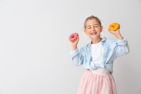 Funny little girl with donuts on light backgroundの写真素材