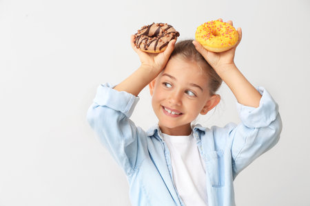 Funny little girl with donuts on light backgroundの写真素材