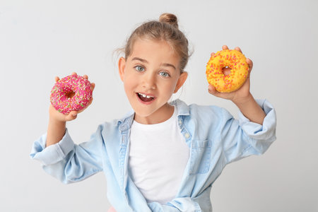 Funny little girl with donuts on light backgroundの写真素材