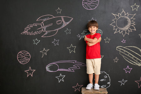 Cute little boy near black wall with drawn spaceの写真素材