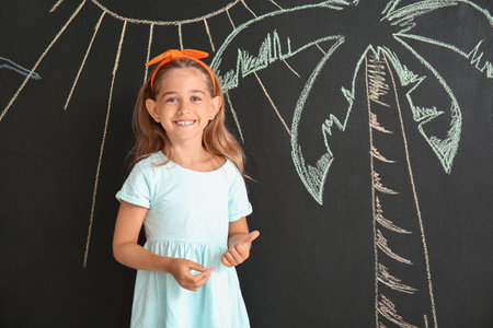 Happy little girl near black wall with drawn palmの写真素材