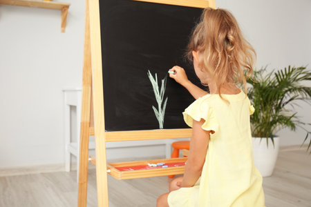 Cute little girl drawing on blackboard in kindergartenの写真素材