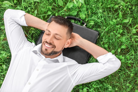 Handsome businessman relaxing in parkの写真素材