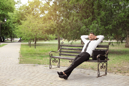 Handsome businessman relaxing in parkの写真素材