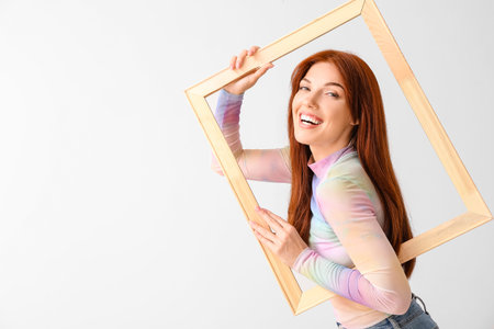 Beautiful redhead woman with frame on light background