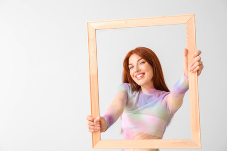 Beautiful redhead woman with frame on light backgroundの写真素材