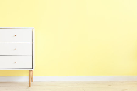 Chest of drawers near color wall in roomの写真素材
