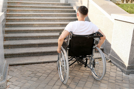 Young man in wheelchair near stairs outdoorsの写真素材