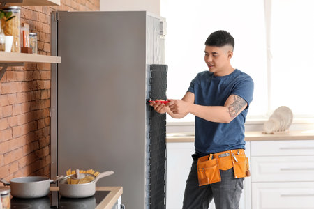 Worker repairing fridge in kitchenの写真素材