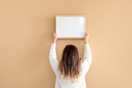 Woman hanging blank photo frame on wallの写真素材