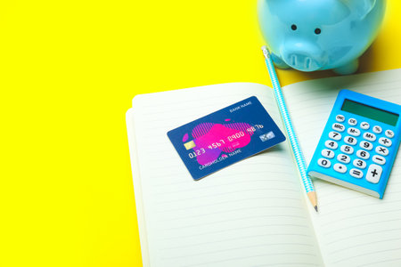 Notebook with credit card, calculator and piggy bank on color backgroundの写真素材
