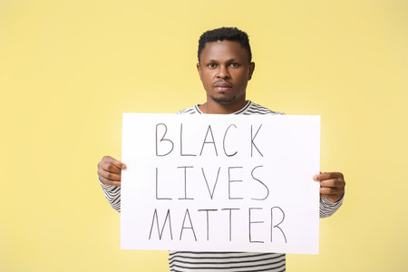 Sad African-American man with poster on color background. stop racismの写真素材