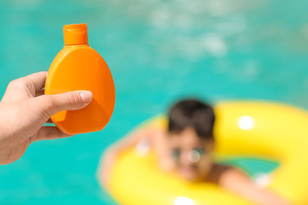 Mother with sun protection cream for her son in swimming pool