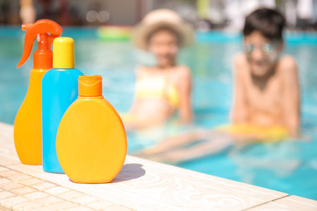 Bottles of sun protection cream near swimming poolの写真素材