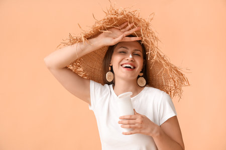 Young woman applying sunscreen cream against color backgroundの写真素材