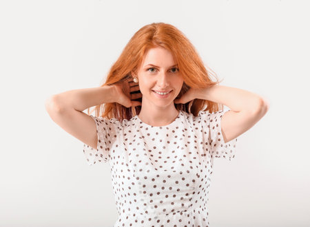 Beautiful young redhead woman on light backgroundの写真素材