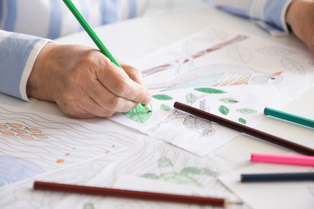 Senior woman coloring picture at table, closeup