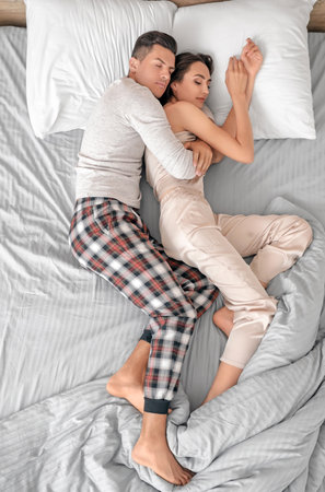 Young couple sleeping in bed, top viewの写真素材