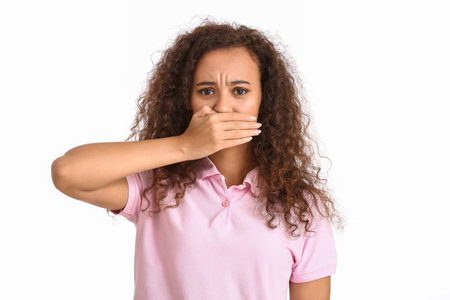 Young African-American woman covering her mouth on white background. stop racismの写真素材
