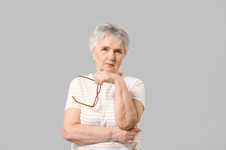 Stylish senior woman on gray backgroundの写真素材