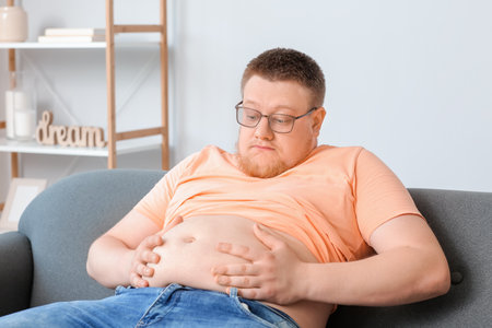 Stressed overweight man at home. weight loss conceptの写真素材