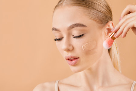Beautiful young woman with foundation on her face against color backgroundの写真素材