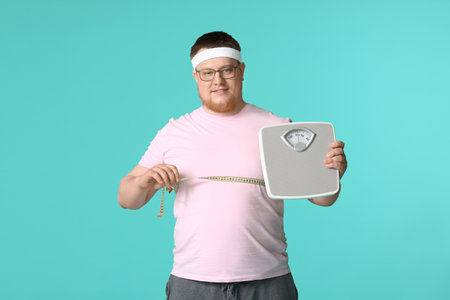 Overweight man with scales and measuring tape on color background. weight loss conceptの写真素材