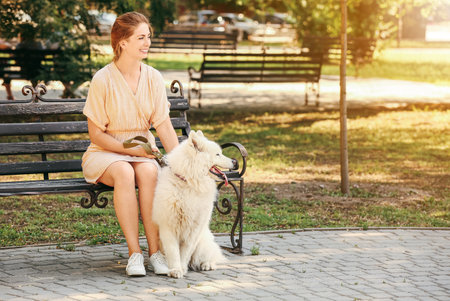 Young woman with cute Samoyed dog in parkの写真素材