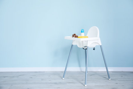 Baby highchair with food and toy on color backgroundの写真素材