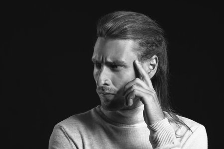 Black and white portrait of handsome man with stylish hairdo on dark background