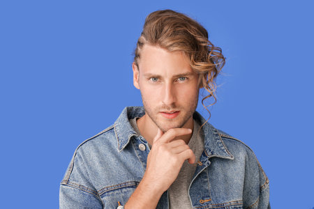 Handsome man with stylish hairdo on color background