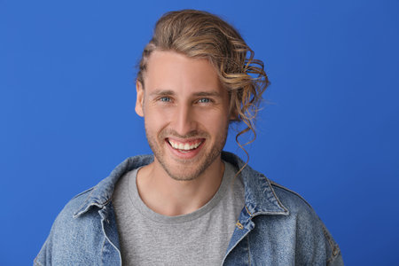 Handsome man with stylish hairdo on color background