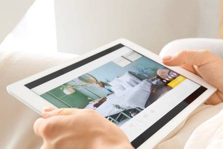 Woman with tablet computer booking room in hotel online, closeup