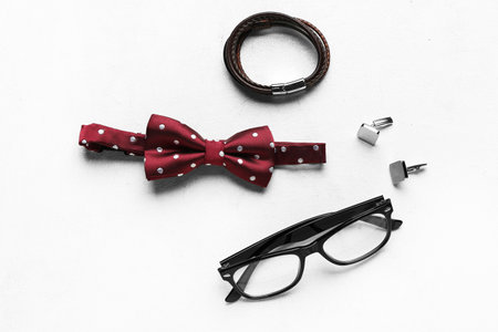 Stylish male bow tie, eyeglasses, cufflinks and bracelet on light backgroundの写真素材