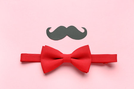 Stylish red bow tie and paper mustache on pink backgroundの写真素材