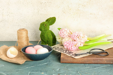 Beautiful hyacinth flowers, Easter eggs and bunny on table near beige wallの写真素材