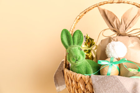 Basket with bunny, Easter eggs and gift bag on beige backgroundの写真素材