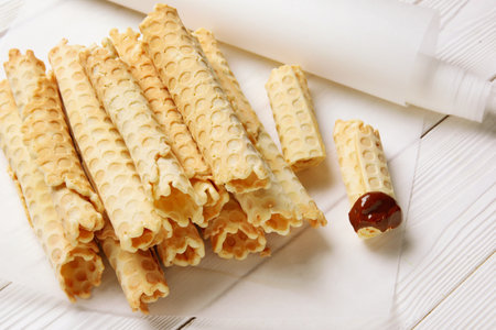 Parchment with delicious wafer rolls on white wooden backgroundの写真素材