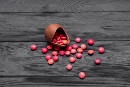 Chocolate Easter egg with candies on gray wooden background